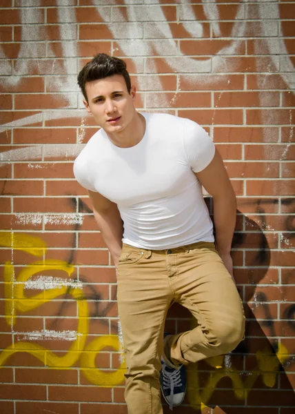 Handsome young man on city brick wall — Stock Photo, Image