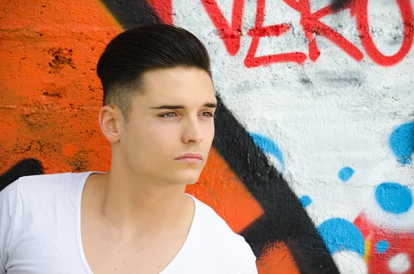 Graffiti duvar karşı iyi görünümlü bir genç adam — Stok fotoğraf