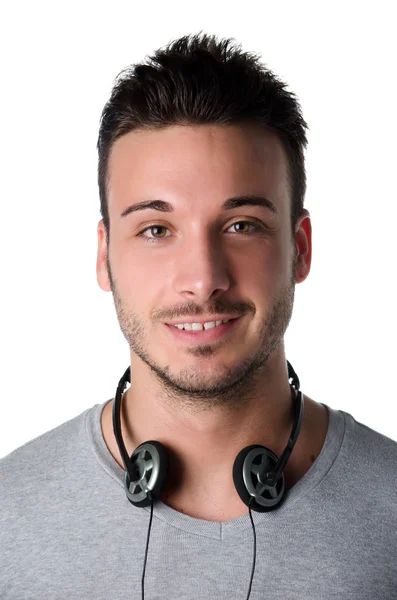 Atraktivní usmívající se mladý muž se sluchátky kolem krku — Stock fotografie