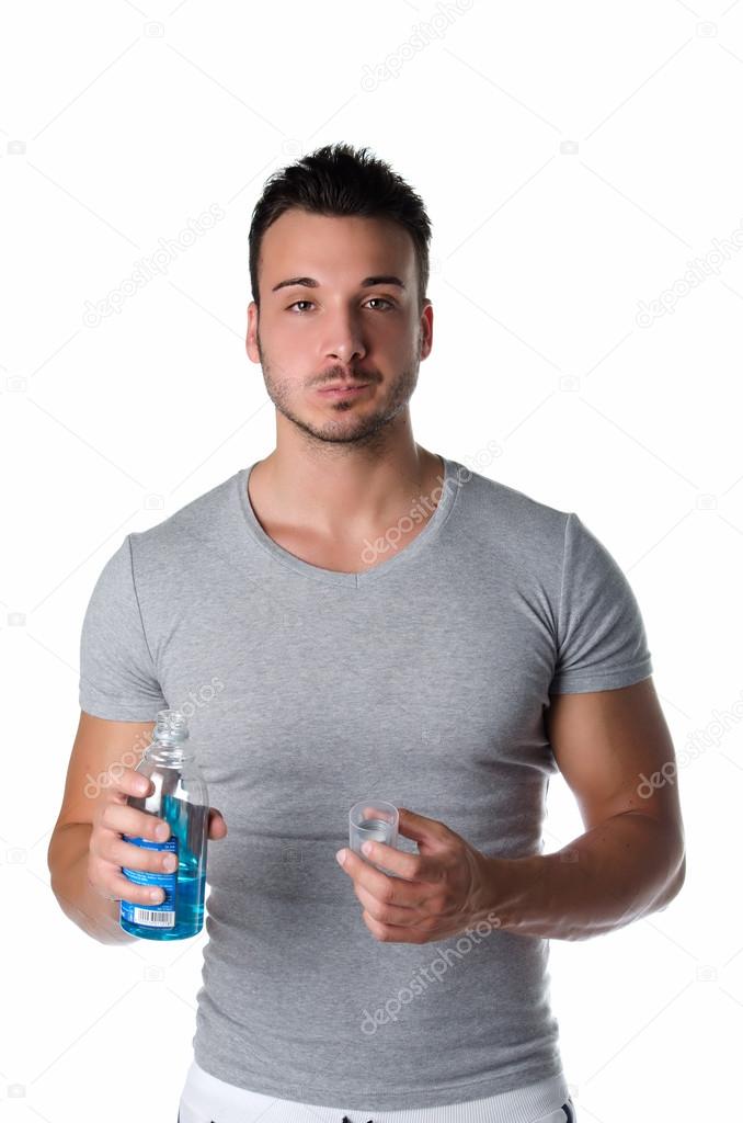 Handsome young man using mouthwash, isolated on white