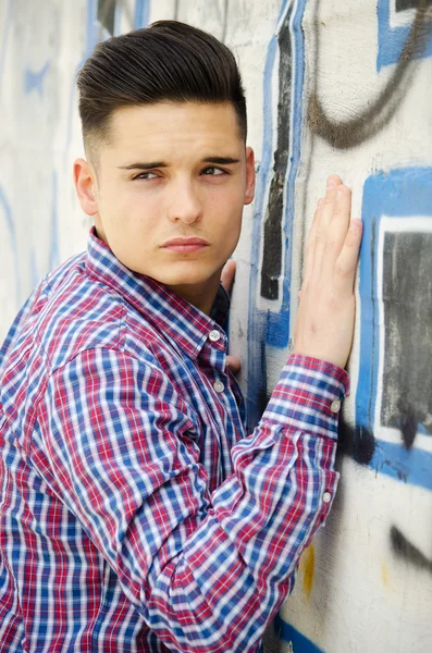 Attraktiv ung man står bredvid färgglad graffiti — Stockfoto
