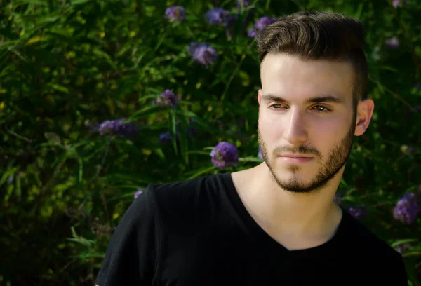 Handsome young man outside, with black t-shirt, large copyspace – stockfoto