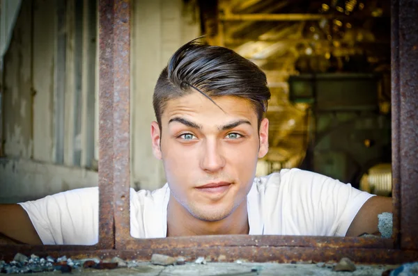 Hübscher junger Mann mit lustigen Ausdruck im rostigen Fenster — Stockfoto