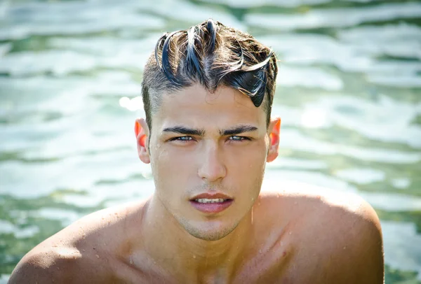 Bello giovane uomo uscire dall'acqua con i capelli bagnati — Foto Stock