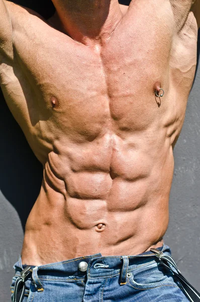 Bodybuilder romp met armen omhoog, geript abs en pecs met tepel piercing — Stockfoto