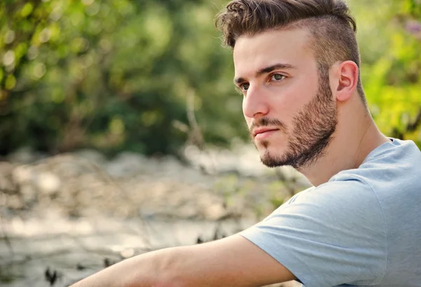 Portrait of handsome young man in white t-shirt in nature — Stock Photo, Image