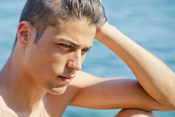 Handsome young man thinking next to the sea — Stock Photo, Image