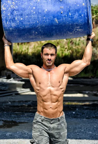 Hot, muscular construction worker shirtless carrying barrel — Stock Photo, Image