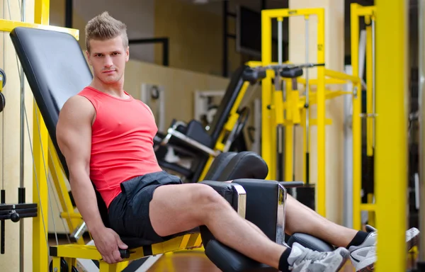 Handsome young man working out on gym equipment — Stock Photo, Image