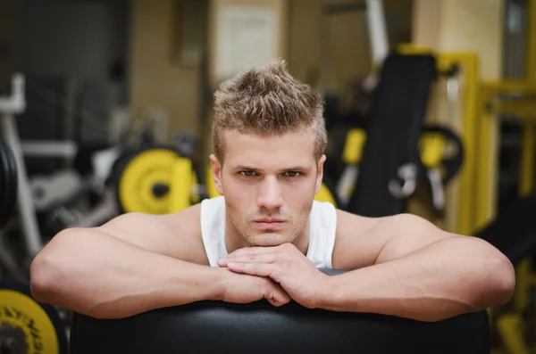 Aantrekkelijke jonge atletische man rustend op gym apparatuur — Stockfoto