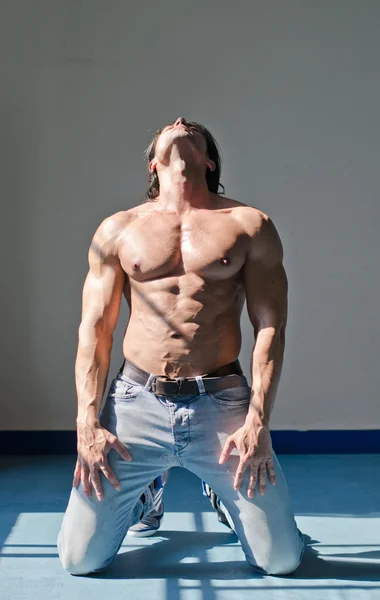 Attraktiv ung man med muskulös kropp, knä och letar upp — Stockfoto