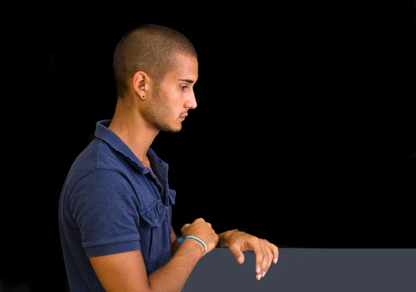 Séduisante jeune homme, vue de côté, regardant vers le bas avec les mains à bord, — Photo