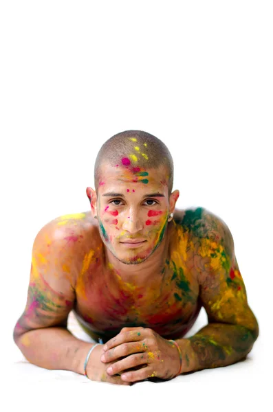 Handsome young man with skin all painted with Honi colors, resting on his elbows — Stock Photo, Image