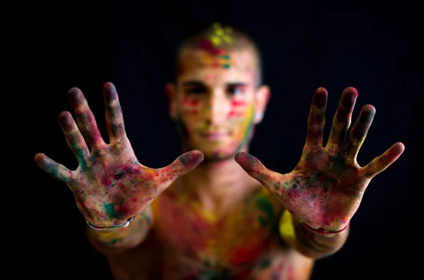 Handsome young man showing hands with skin all painted with colors — Stok fotoğraf