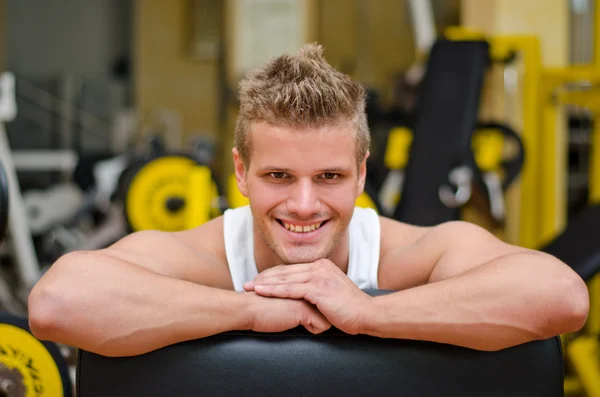 Attraktiv ung man i gym vilar på gymutrustning — Stockfoto