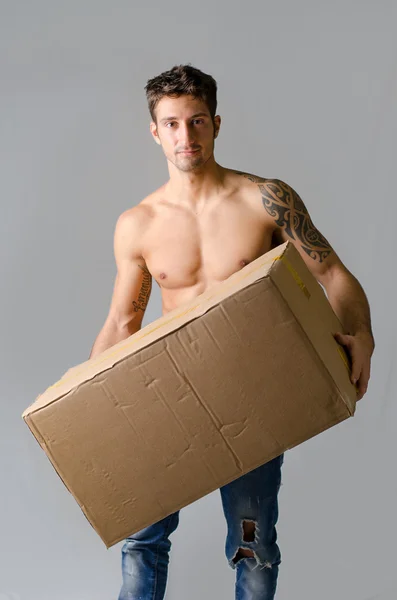 Handsome, athletic, shirtless young man carrying big cardboard box — Stock Photo, Image