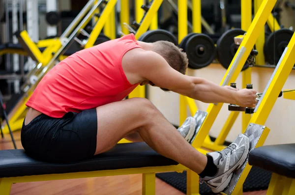 Handsome young man working out on gym equipment — Stock Photo, Image