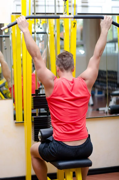 Spor aletleri üzerinde çalışan yakışıklı genç adam. — Stok fotoğraf