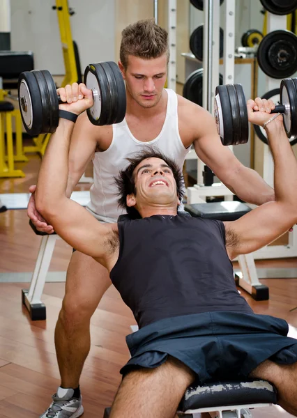 Personal trainer helping client in gym — Stock Photo, Image
