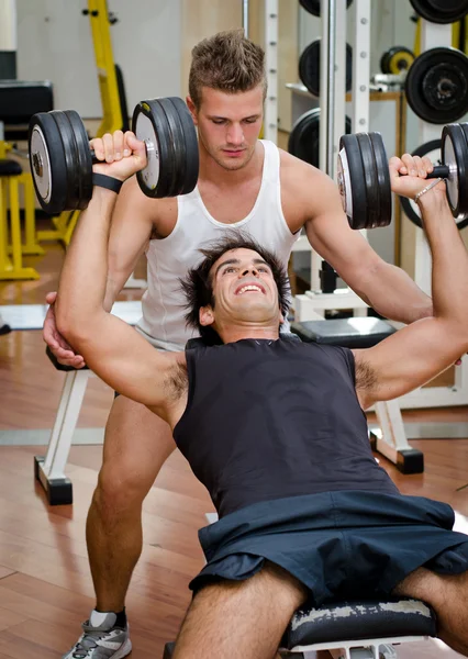 Entraîneur personnel aidant client dans la salle de gym — Photo