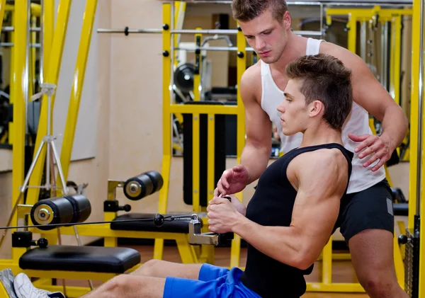 Entraîneur personnel aidant client dans la salle de gym — Photo