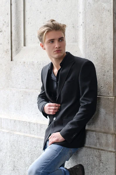 Handsome blond young man leaning against white wall — Stock Photo, Image