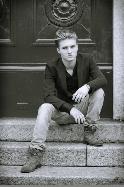 Attractive blue eyed, blond young man sitting on stair steps — Stock Photo, Image