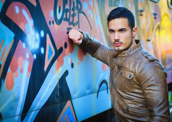 Pohledný mladý muž vedle kryté graffiti zeď — Stock fotografie