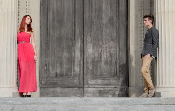 Elegant young couple separated by big wooden door — Stock Photo, Image