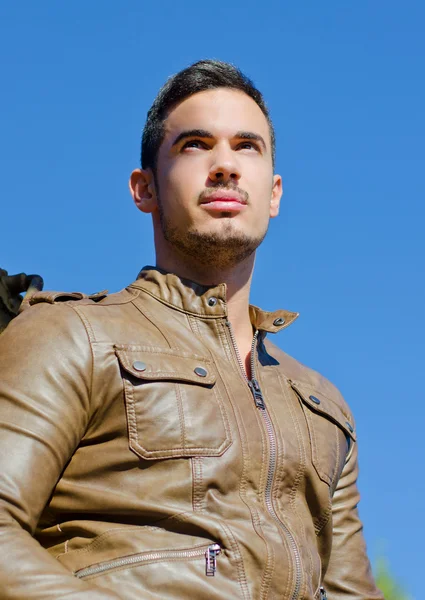 Handsome young man in leather jacket against blue sky — Stock Photo, Image