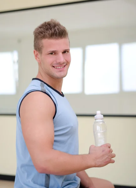 Attractive, nice male athlete holding plastic bottle of water — Stock Photo, Image