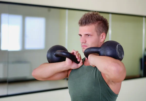 Joven guapo hacer ejercicio en el gimnasio con kettlebells —  Fotos de Stock