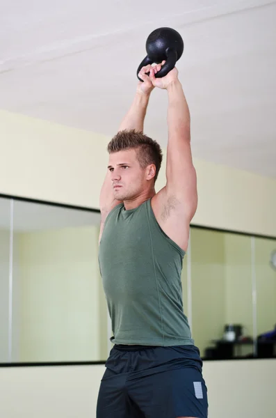 Jovem bonito malhando na academia com kettlebell — Fotografia de Stock