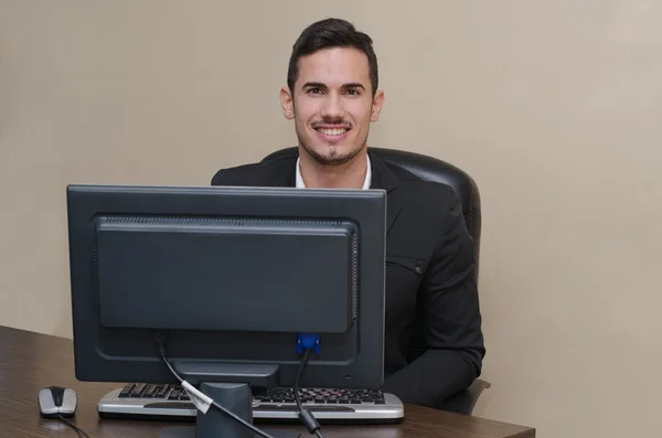 Vriendelijk, glimlachend jonge zakenman zit aan Bureau — Stockfoto