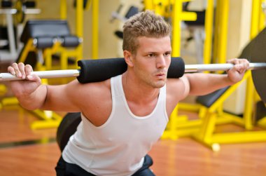 spor salonunda squats yaparken yakışıklı genç