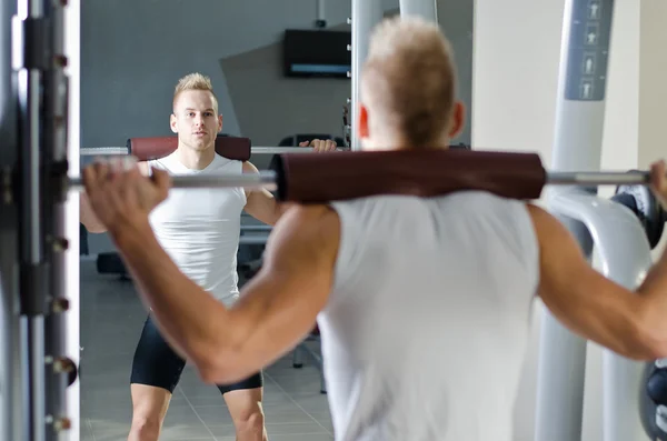 Knappe jonge man doen squats in gym — Stockfoto