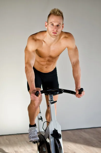 Bonito jovem fazendo spinning na bicicleta — Fotografia de Stock