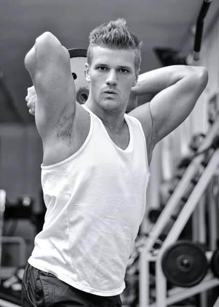 Attractive young man training triceps, lifting weight over his head — Stock Photo, Image