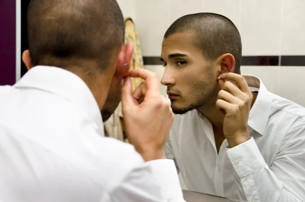 Handsome young man looking at ear piercing — Stock Photo, Image