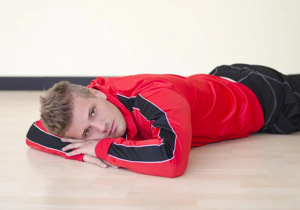 Séduisante jeune homme couché sur le sol portant costume gym — Photo