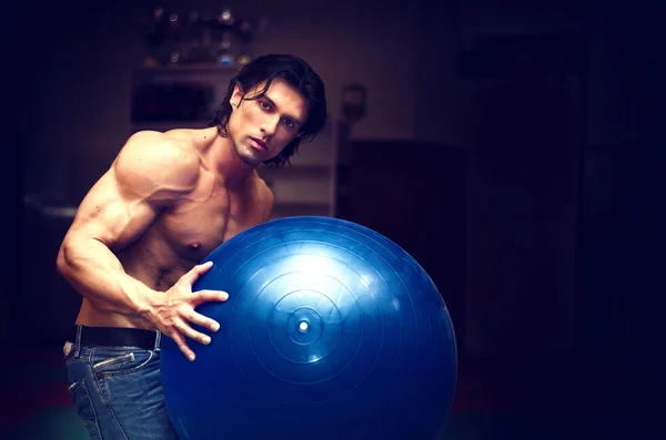 Homem jovem musculoso e sem camisa segurando uma bola de fitness — Fotografia de Stock