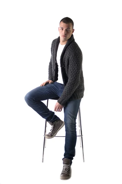 Jovem atraente, sentado na cadeira com o suéter de lã e calças de brim — Fotografia de Stock