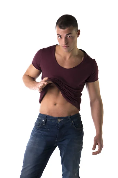 Handsome young man pulling up t-shirt, showing abs — Stock Photo, Image
