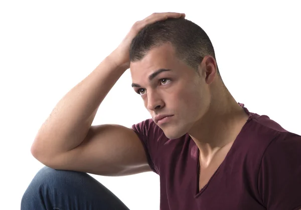 Beau jeune homme avec t-shirt et jeans, assis, main, toucher sa tête — Photo