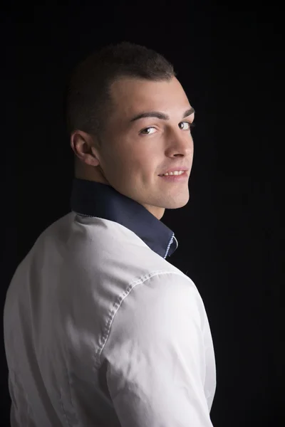 Attraktiver junger Mann mit weißem Hemd, lächelnd auf Kamera umdrehen — Stockfoto