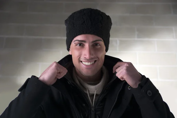 用羊毛帽子和冬季外套，在室内的年轻男人微笑着 — 图库照片