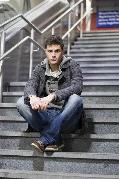Handsome young man sitting on stairs — Stock Photo, Image