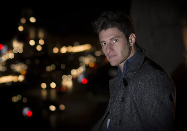 Vonzó fiatal férfi portré, éjszakai város fényei háta mögött — Stock Fotó