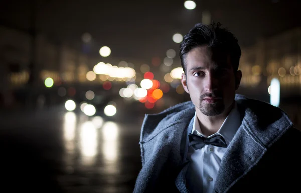 Attractive young man portrait at night with city lights behind him