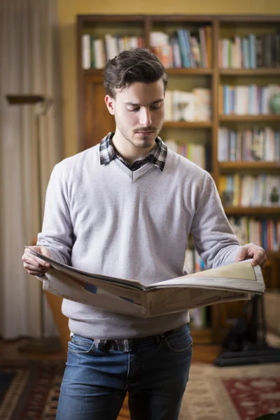 Jovem bonito, lendo o jornal em casa — Fotografia de Stock